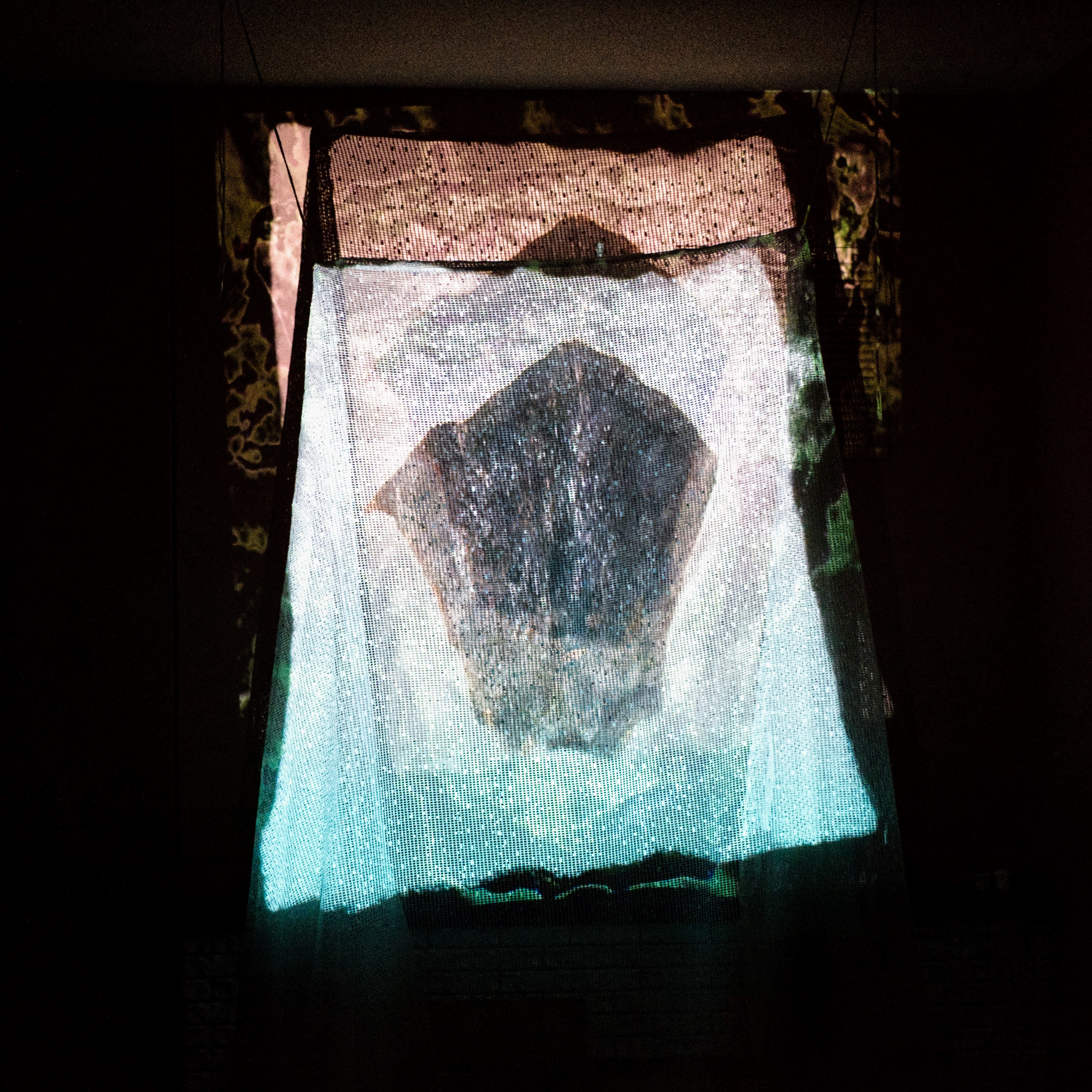 A still from a video of algorithimically generated stones projected onto a lace mesh